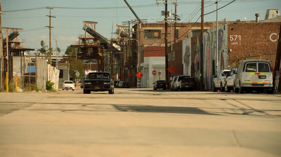 Darius drives Alex down the street towards the warehouse.