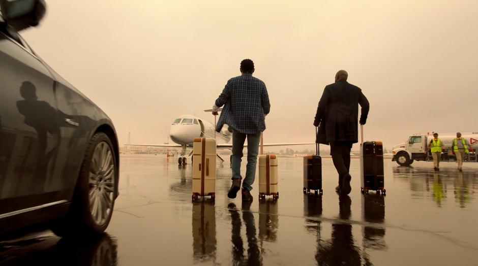 Alex and Geoffrey wheel their suitcases towards the plane.