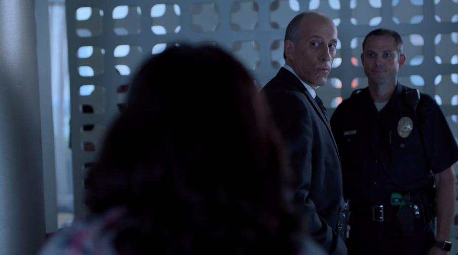 Detective Flores turns as Tamar walks in to the hotel room.