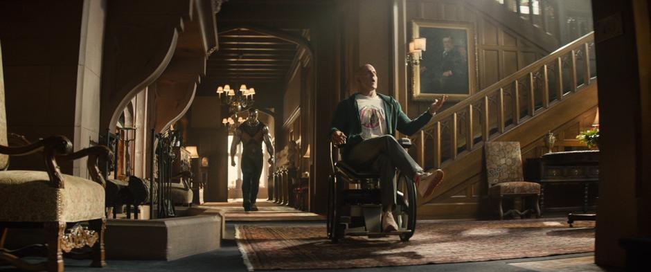 Colossus follows Wade as he rolls into the lobby on Xavier's wheelchair.