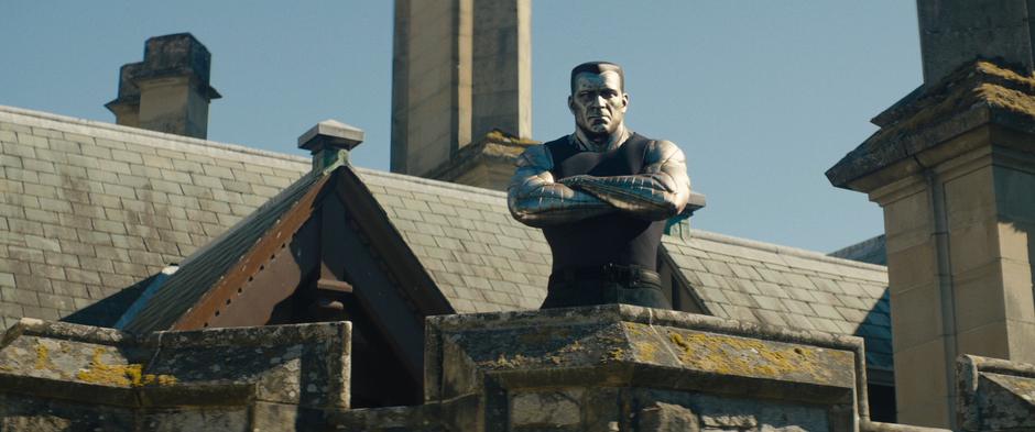 Colossus stares down from the upper balcony with his arms crosses.