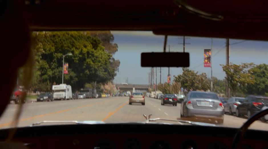 Topher's car is visible through the windshield weaving through traffic.