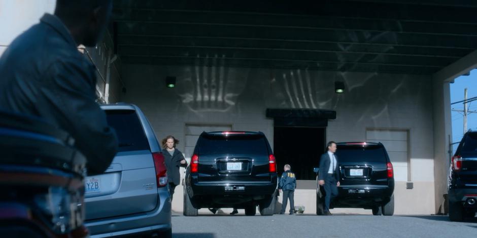 Jeff leans against the truck as Philip and Grant walk out of the building.