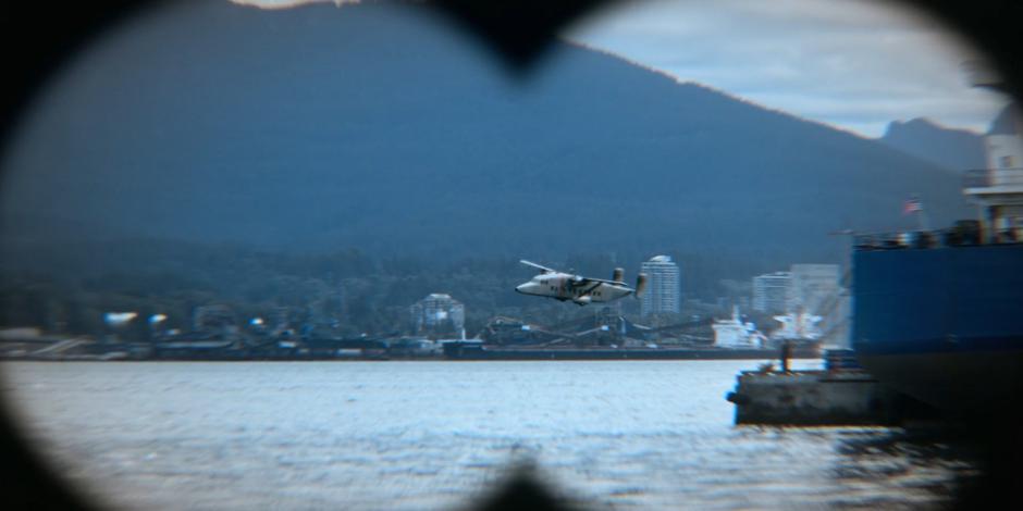 The terrorist's plane is visible through the binoculars flying low over the water.