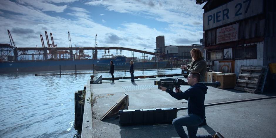 Grant and Marcy stand on the other side of the pier while Trevor prepares the rocket launcher and Philip counts down the time.