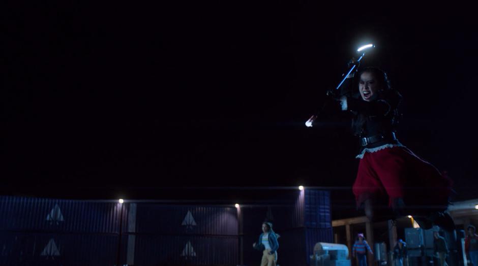 Nico leaps through the air at Jonah with her staff coated in the serum.