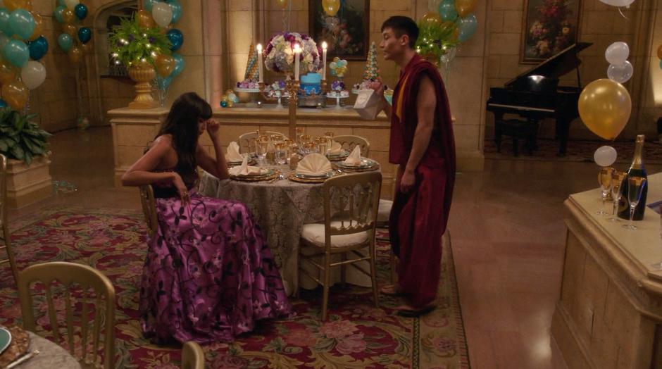 Jason offers Tahani leftovers from the other party while she mopes at a table.