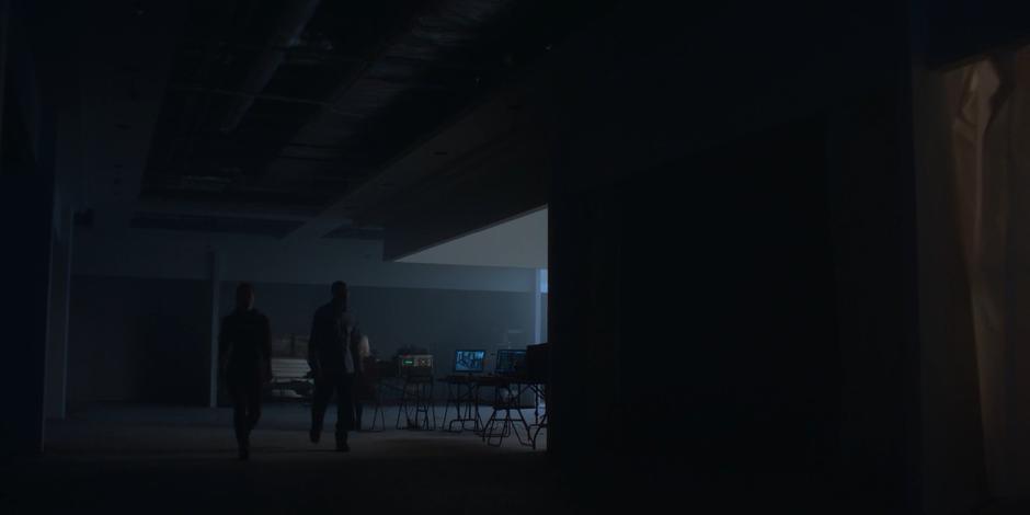 Dawn leads Jeff through the darkened basement past a computer setup.