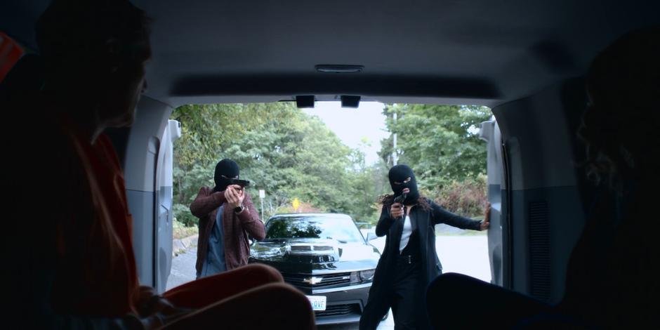 Trevor and Carly open the back of the police van wearing ski masks and holding guns to take Andrew Graham from Joanne.