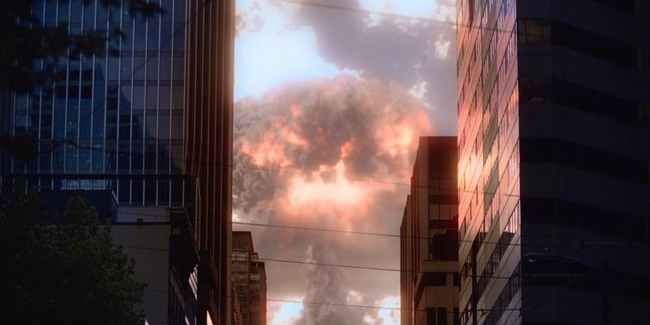 A giant mushroom cloud fills the sky at the end of the street.
