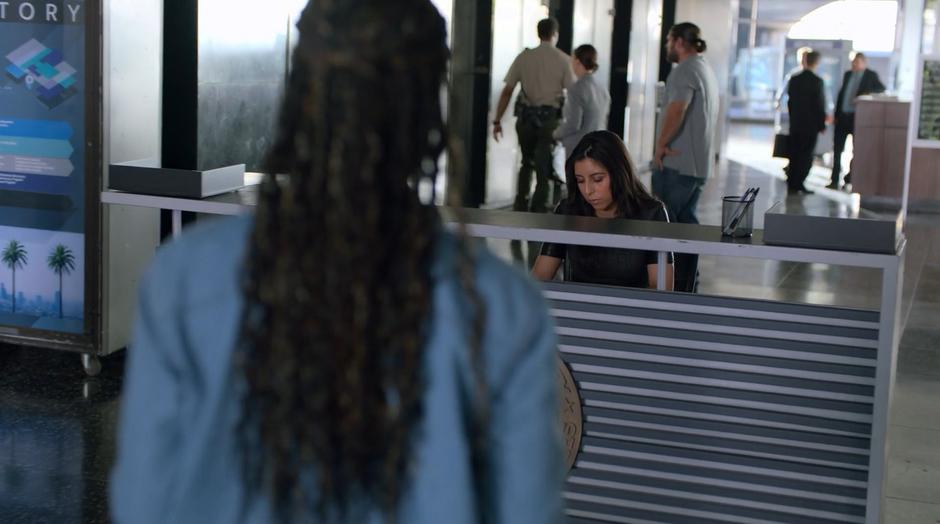 Livvie approaches the reception desk to present her evidence.