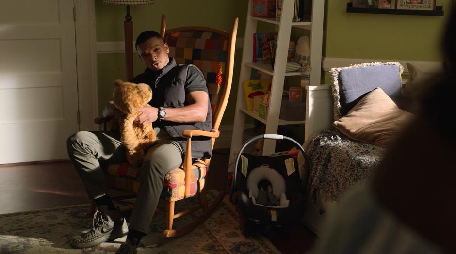 AWOL talks to Tamar fromt he rocking chair where he is sitting and holding a teddy bear.