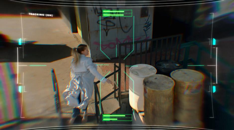 Karolina is filmed by a drone climbing up onto the loading dock towards the door into the warehouse.
