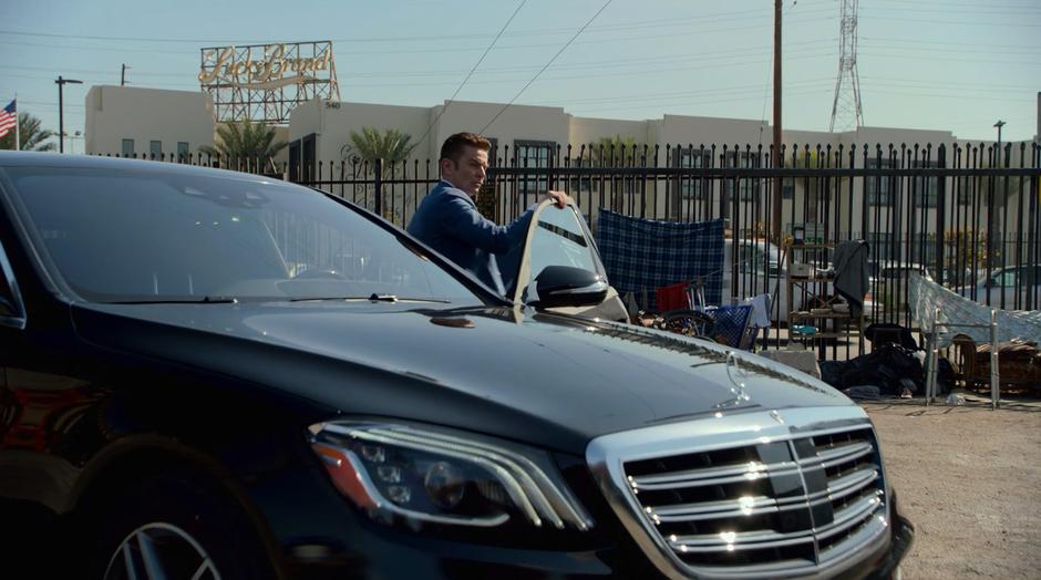 Victor steps out of his car in the parking lot of the warehouse.