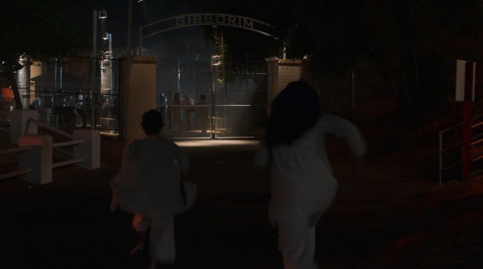 Nico and Molly run towards the compound's gate.