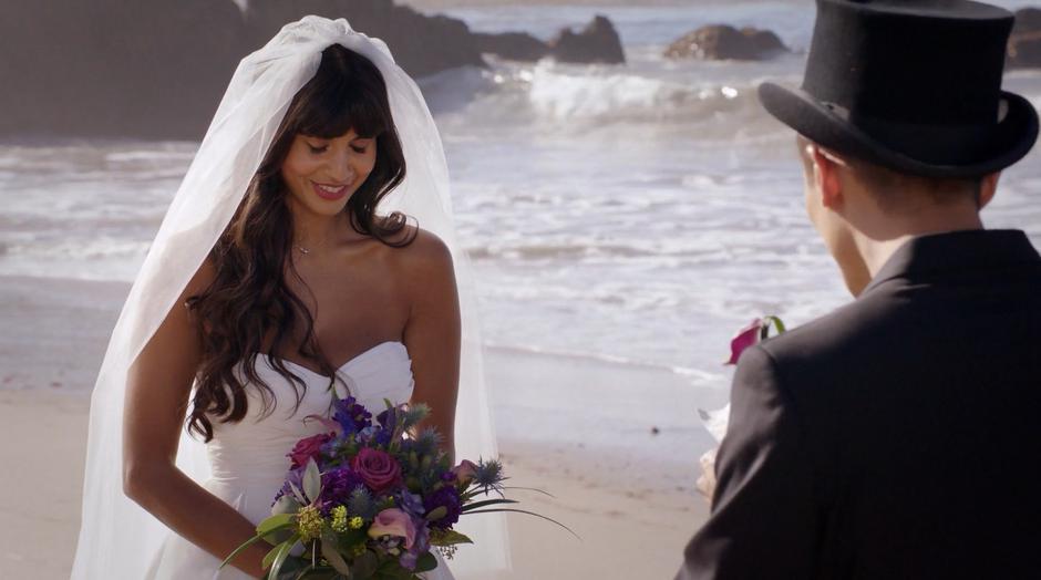 Tahani looks down and smiles while Jason gives his vows.