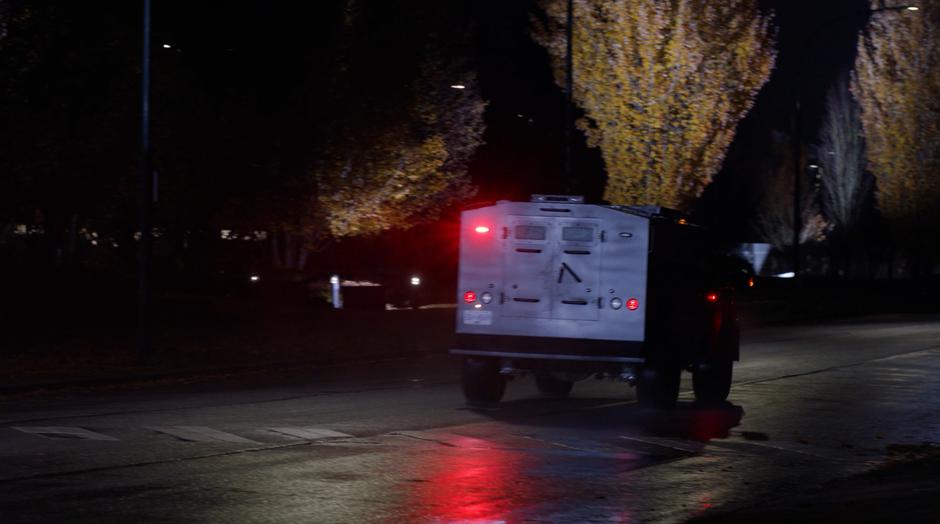 The armored car drives down the street with its lights flashing.