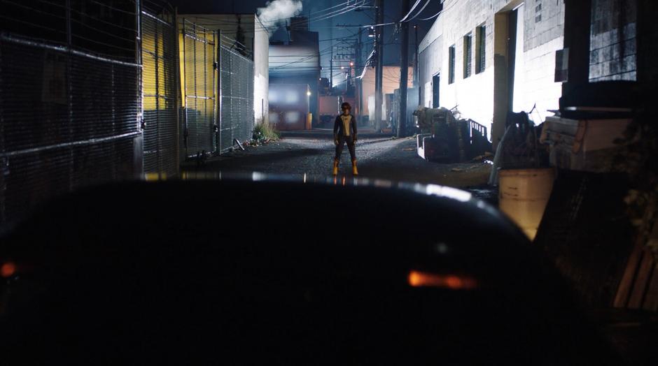 Nora stands in the middle of the alley in the way of the stealth car.