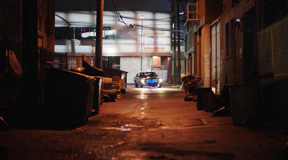 The stealth car turns the corner and heads down the alley.