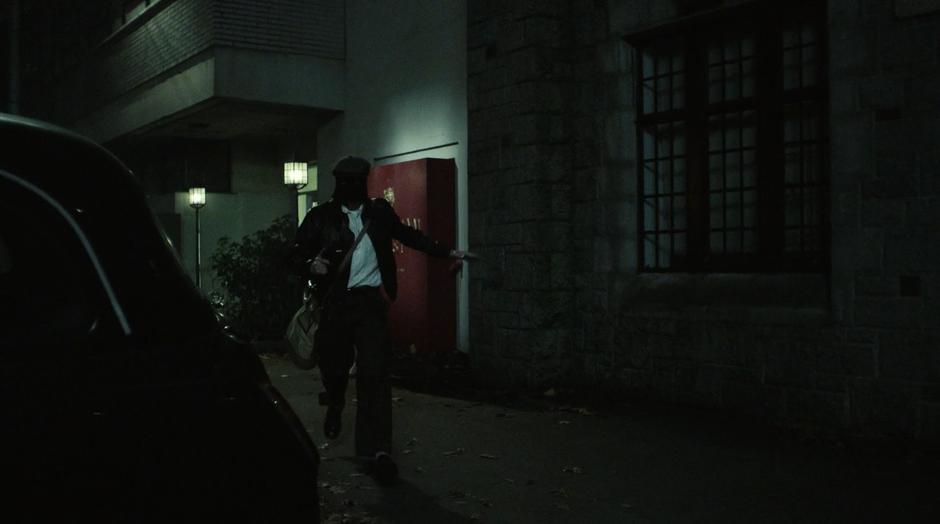 A masked Harry walks away from the bank holding a gun.