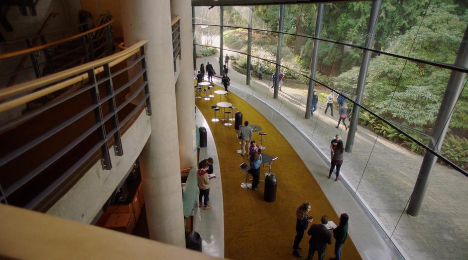 Macy and Galvin talk while walking through the glass-walled lobby.