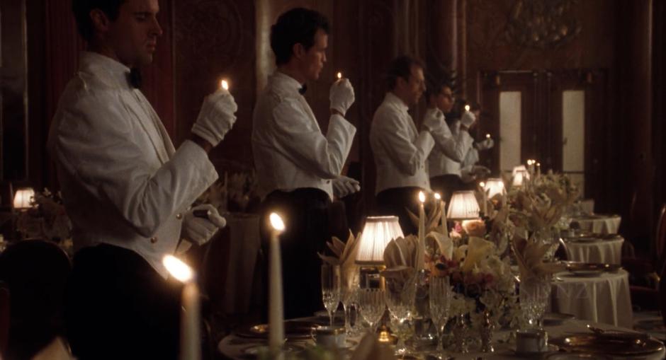 A line of staff members light the candles in the dining room.