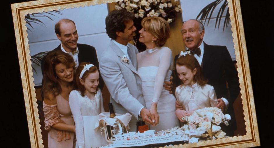 Nick and Liz cut their cake while standing with their daughters and other family during their 1998 wedding.
