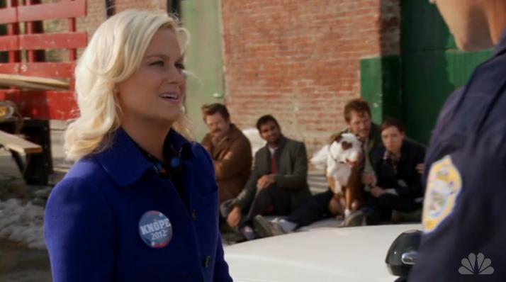 Leslie Knope talks to the cop after Ron Swanson and other employees were pulled over on their way to Leslie's comeback tour.