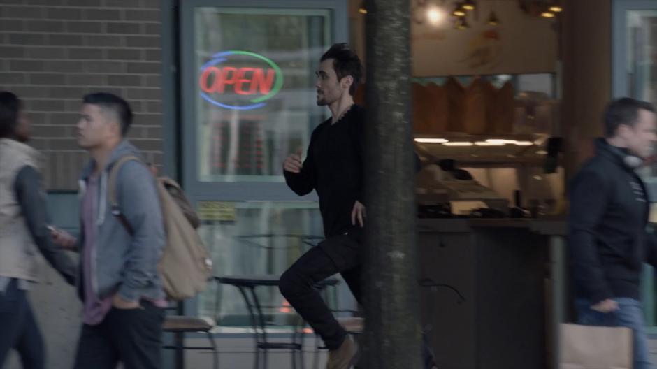 Mark runs down the sidewalk past several pedestrians.