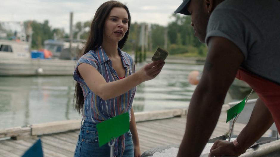 Ryn holds out a dollar to the man selling his fish.