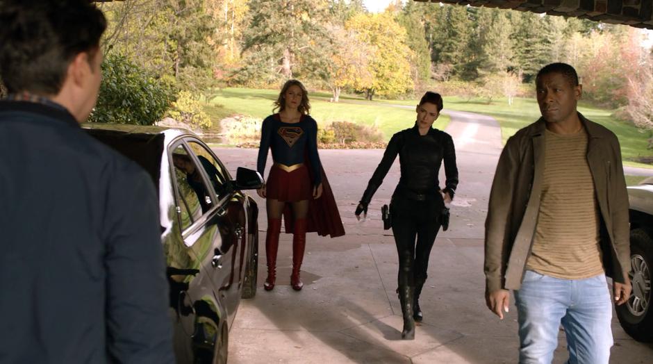 Kara, Alex, and J'onn approach General Tan as he is packing up his car.