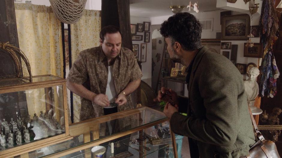 The store owner pulls out a set of antique pitch pipes for Mr. Morales.