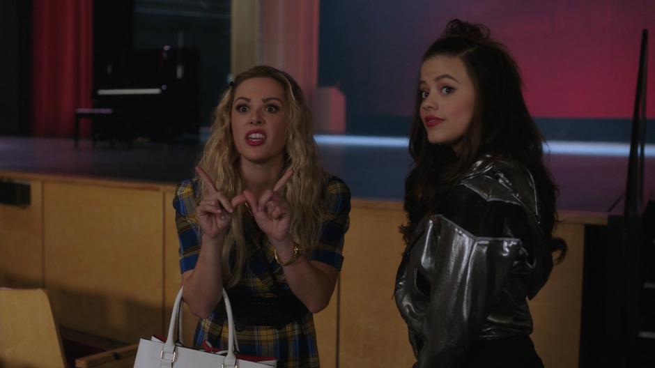 Lucy makes a hand gesture at Effie while turning from her conversation with Maggie.
