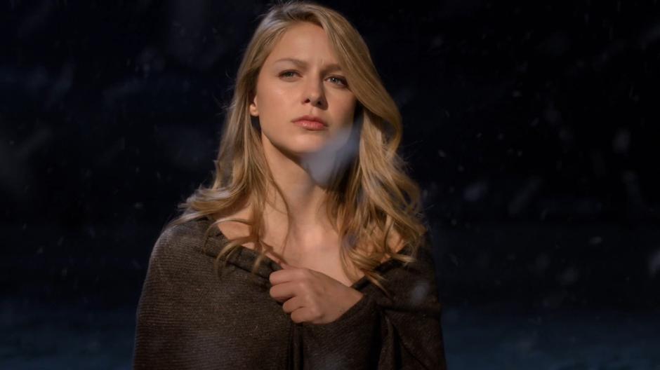 An alternate Supergirl walks into the light wearing only a blanket.