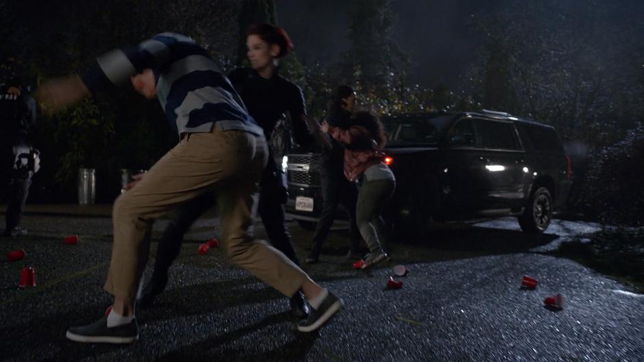 Alex fights one of the frat guys while Brainy helps a bystander get to safety.