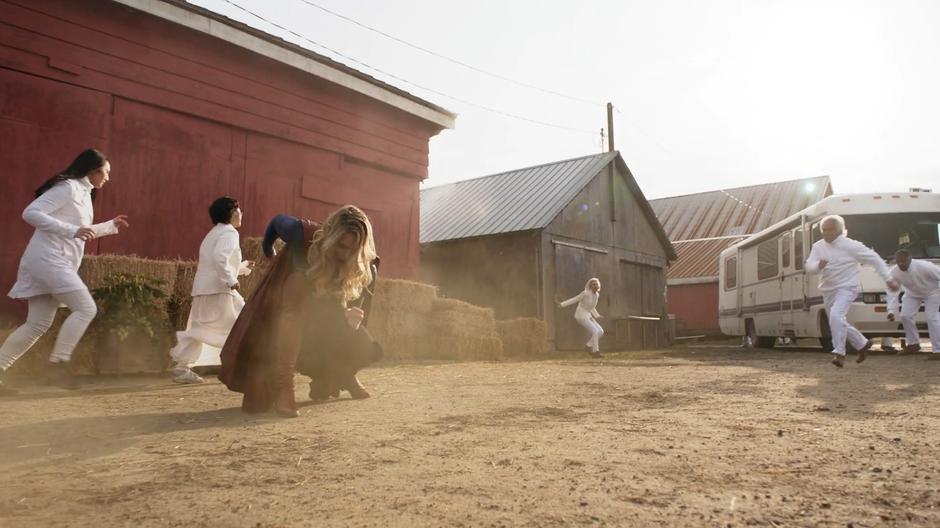 Kara lands outside the barn as townspeople run around in a panic.