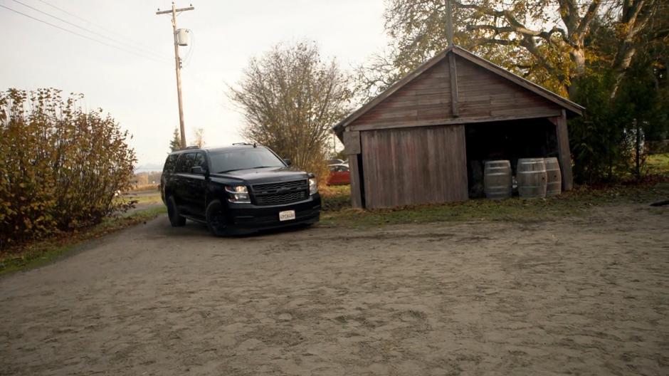 A DEO SUV pulls into the dirt lot in front of the barn.