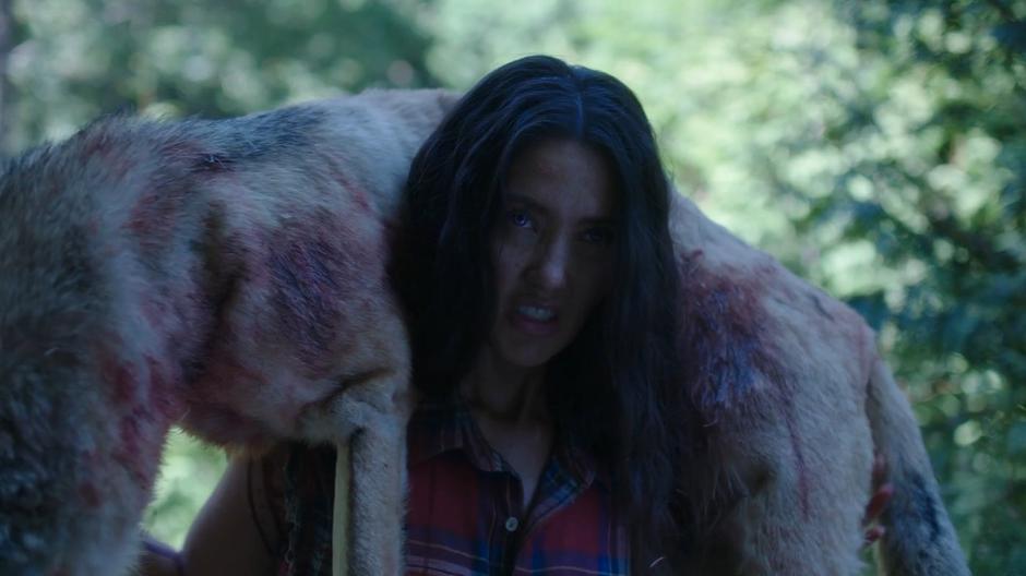 Katrina walks into the clearing holding the dead wolf.