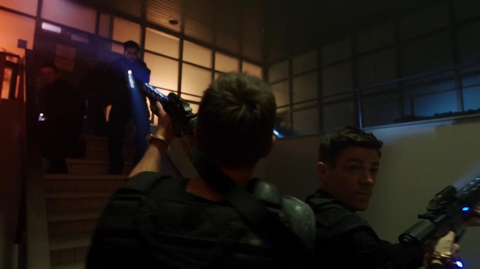 Ralph and Barry stand on the stairs shooting at the goons who surround them.