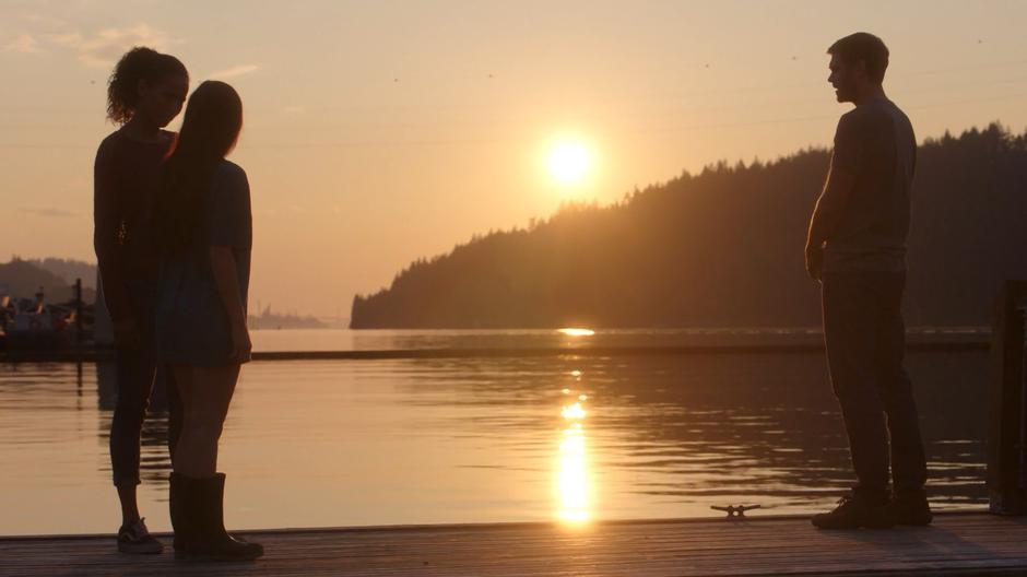 Maddie talks to Ryn with Ben while they stand on the dock at sunset.