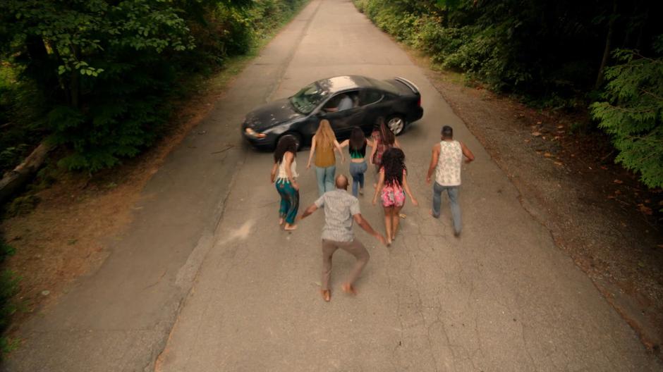 A car swerves to a stop in front of the mermaids who have run out onto the road.