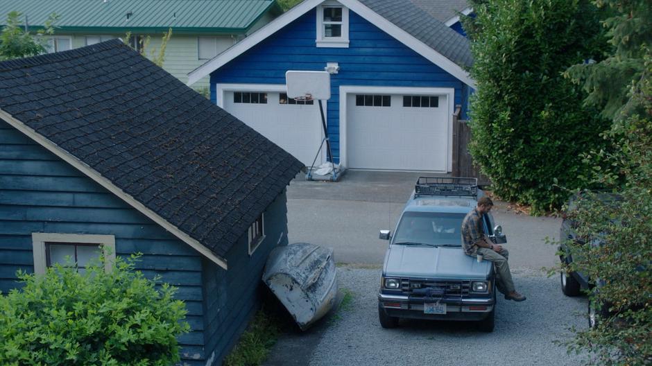 Ben sits on the hood of his truck with his coffee for Maddie.