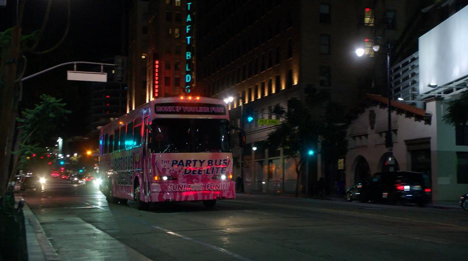 The party bus drives off down the street at night.