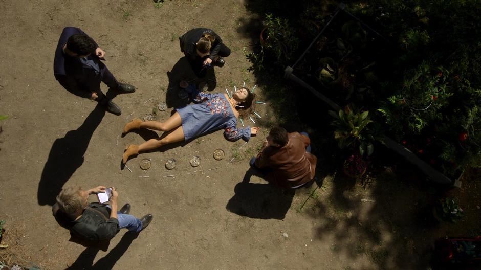 Lucifer, Chloe, Reese, and Dan look at the body surrounded by implants and botox syringes.