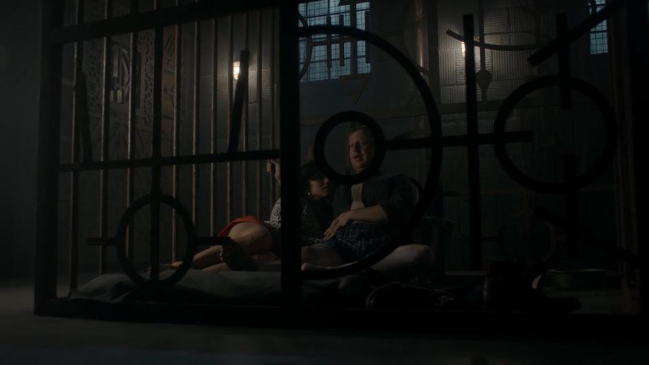 Margo lays up against Josh as they sit against the cell bars after having sex.