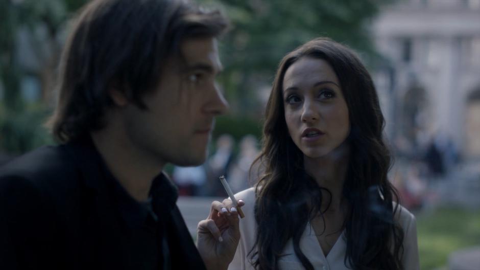 Julia talks to Quentin while holding a cigarette.