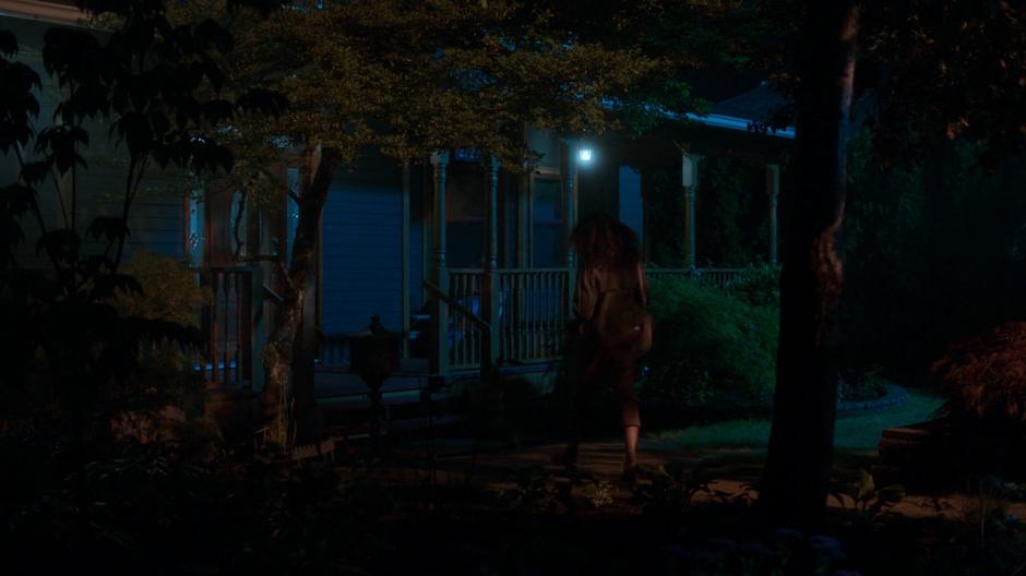 Susan walks to the front door of the house at night.