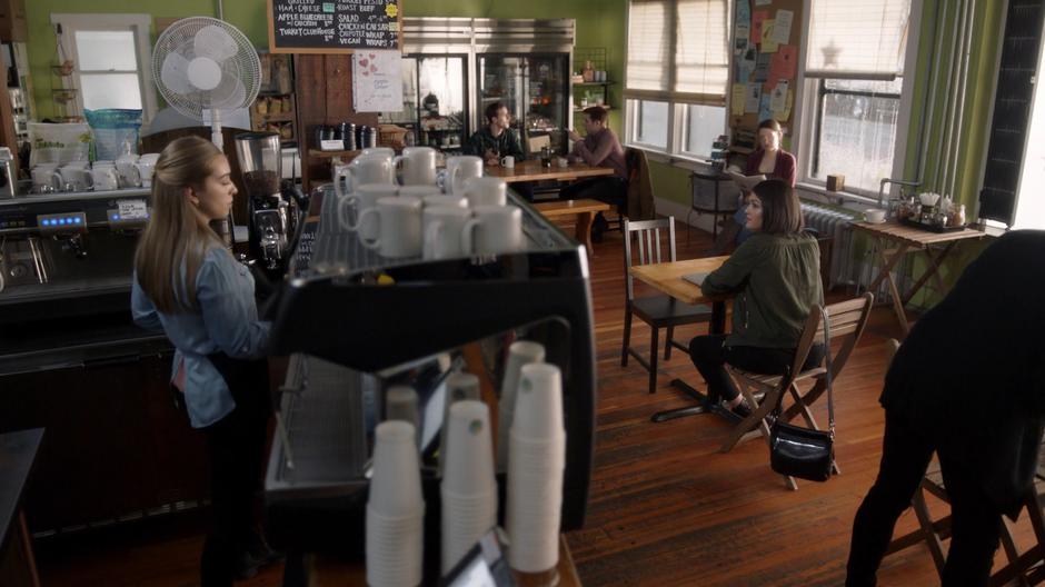 Niko sits at the table in the middle of the coffee shop waiting for Mel.