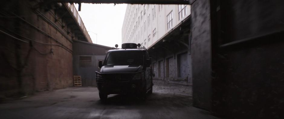 The van drives through the alley following the line of ants.