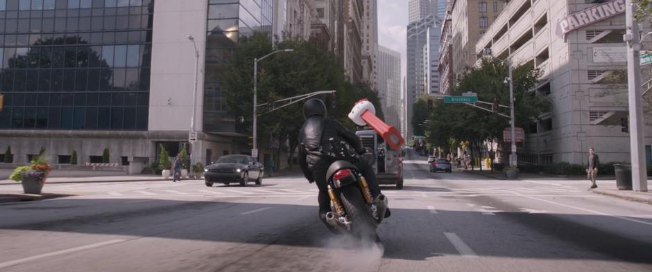 A motorcyclist tries to dodge out of the way as a Hello Kitty Pez Dispenser enlarges and flies back towards them.